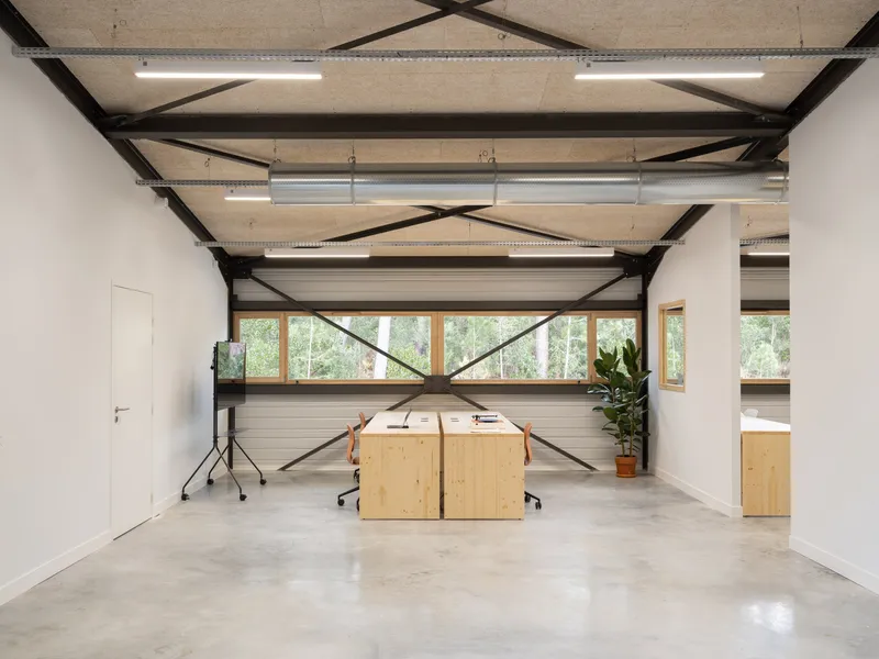 Steel cross-bracing spanning workspace with timber desks and continuous horizontal window