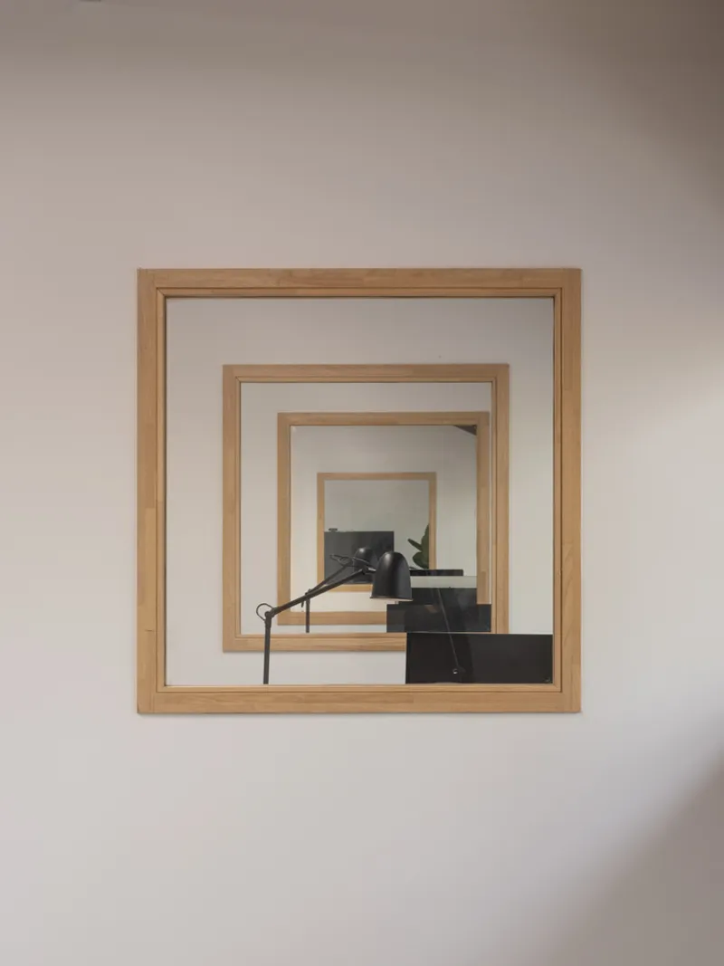 Interior wall opening with nested timber frames revealing a black staircase through layered portals