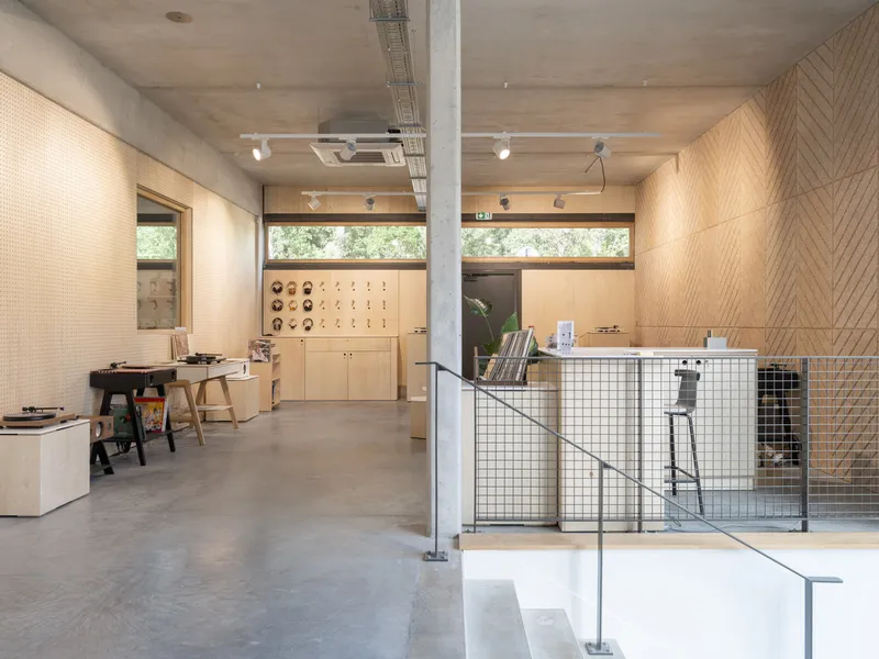 Interior showroom with pegboard walls, exposed concrete ceiling, and wire mesh stair railing