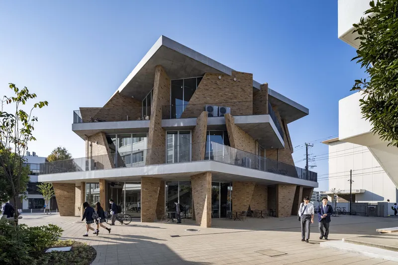 Corner view showing cantilevered concrete slabs, angled brick columns and pedestrians on the ground level plaza
