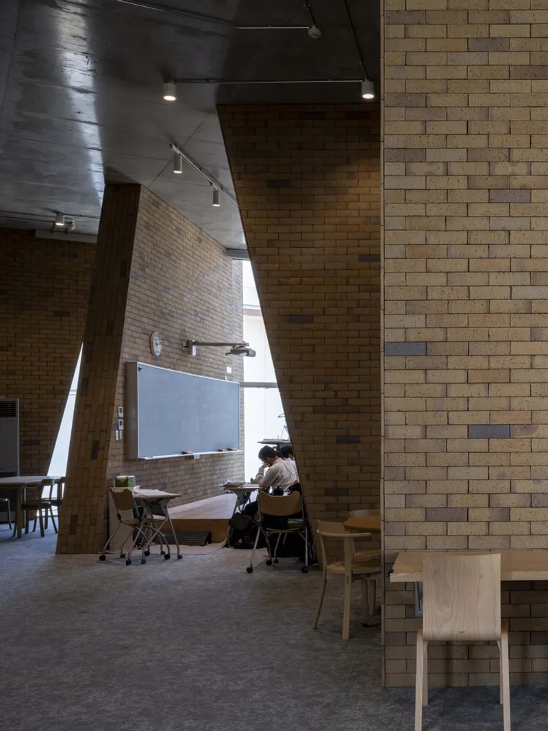 Double height interior with brick walls and timber columns illuminated by natural light from above