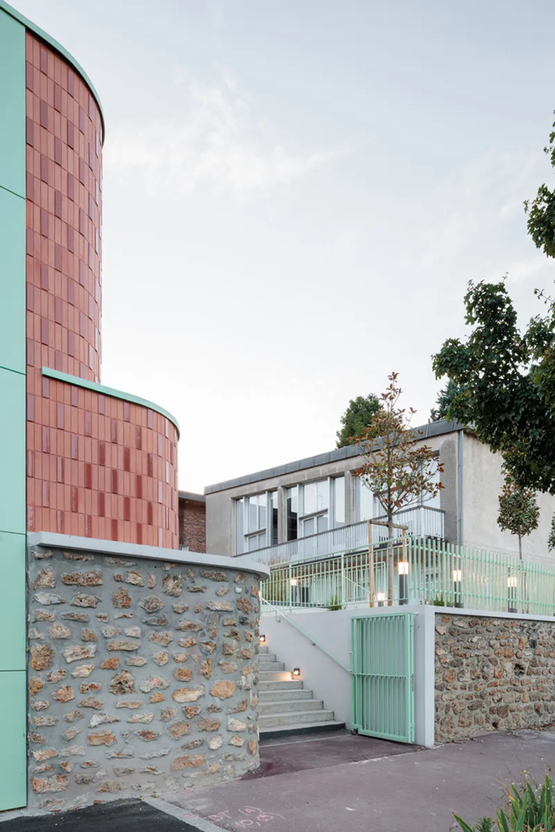 Connection: coral terracotta tower, pale green metal stair, original stone rubble wall, glass balustrade