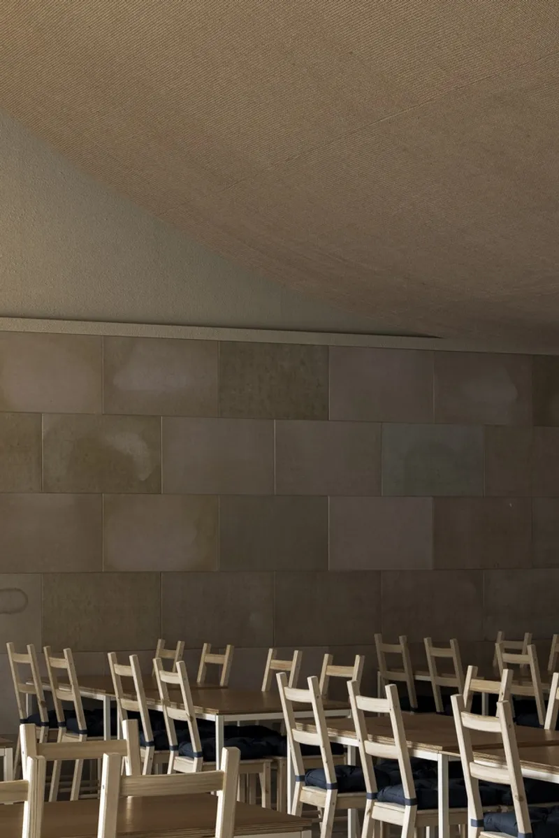 Wall and seating: concrete block wall with lacquer paper panels in varying tones, pale timber chairs below