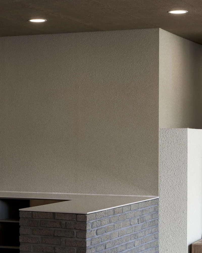 Kitchen partition: plastered volume above brick counter, recessed light, dark service area behind