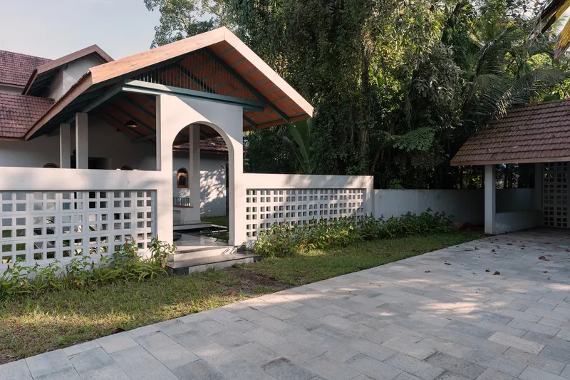 Entry courtyard with white lattice screen wall and terracotta roof pavilion in afternoon light