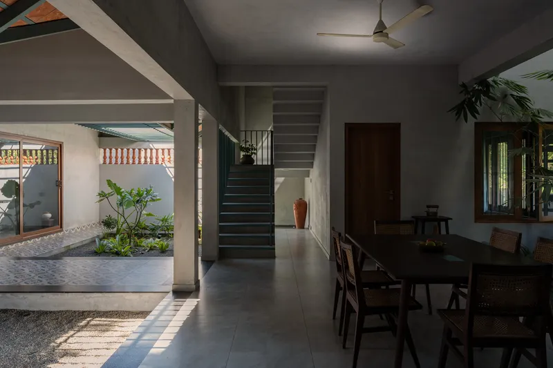 Interior dining room opening through a wide portal to an internal courtyard with planted beds