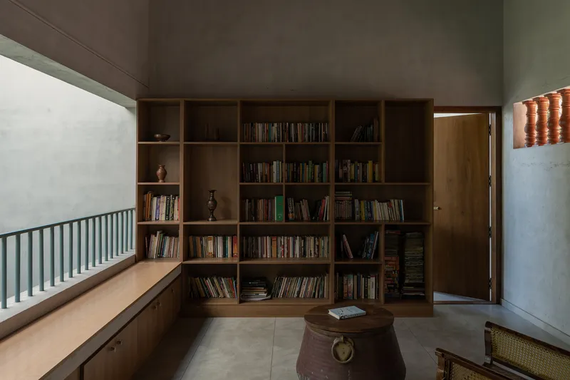 Upper level library with built-in timber bookshelves and a green metal railing along the window
