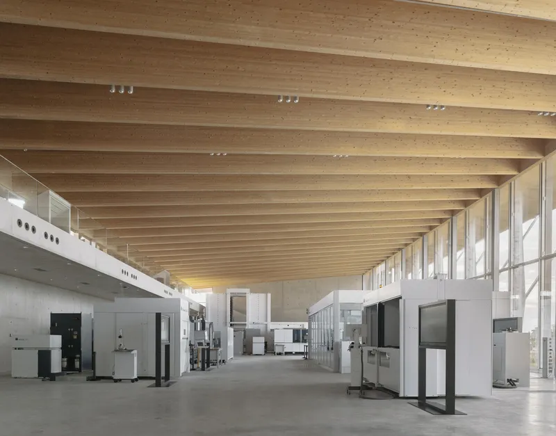 Exhibition hall with exposed timber ceiling beams, track lighting, and display cases on concrete floor