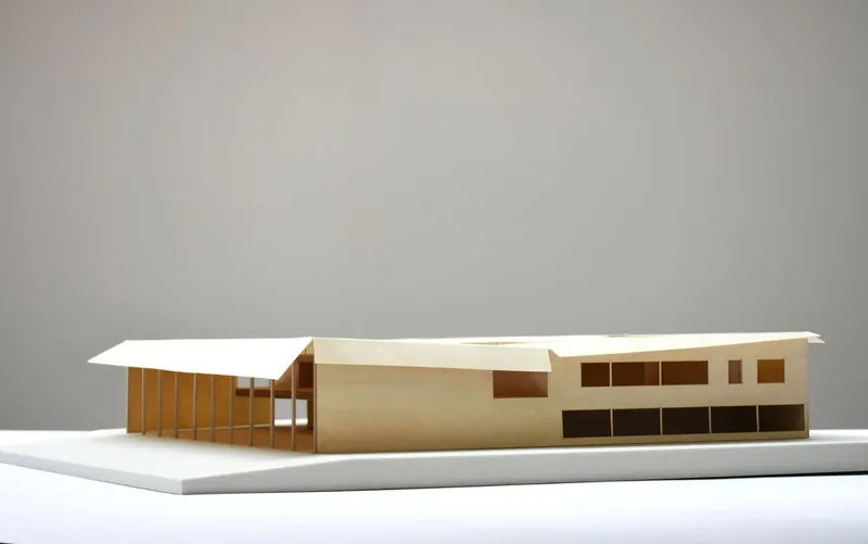 Physical model showing the angled roof and timber column rhythm on a white plinth