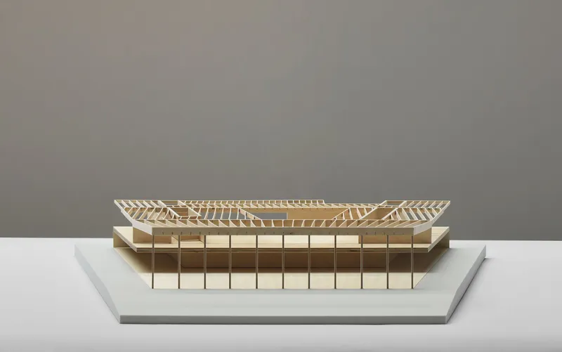 Physical model showing the exposed timber roof structure and glazed facade in neutral light
