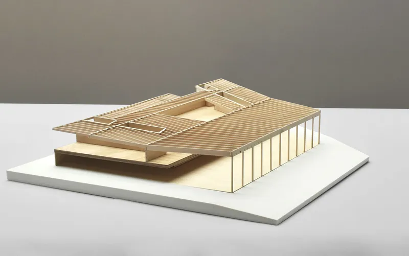 Physical model from opposite angle showing central courtyard opening and layered roof surfaces with timber slats