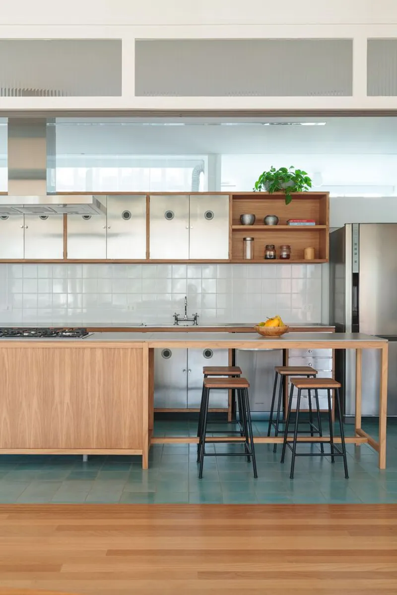 Kitchen: oak and stainless steel island with gas hob, bar stools, white tile backsplash, open shelving, blue-green floor tiles