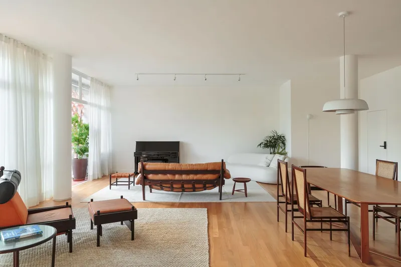 Open plan: living room with leather sofa and piano, dining area with rosewood table, white pendant lamp, cobogó light, oak floor