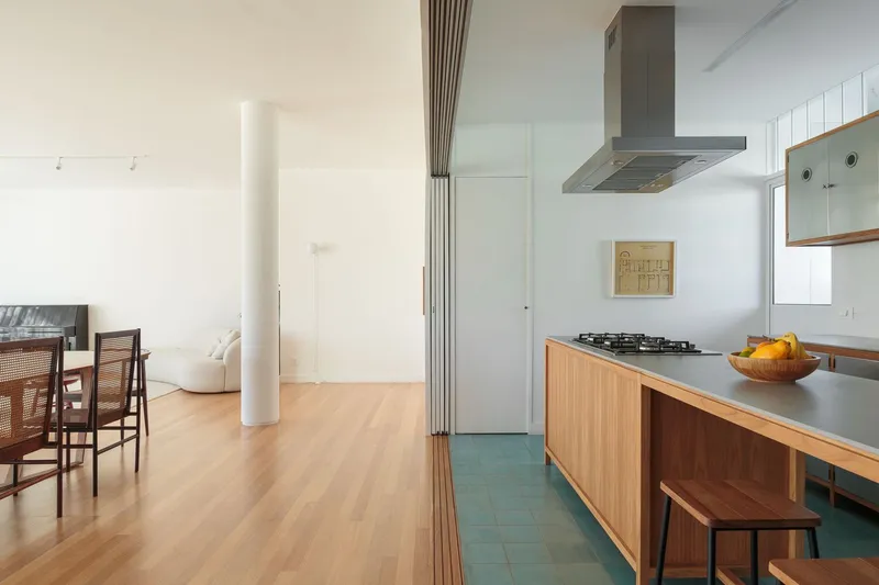 Kitchen detail: stainless steel counter, gas hob, oak island, fruit bowl, corridor to bedroom visible, white column