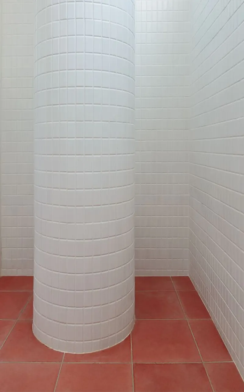 Column detail: cylindrical column clad in small white square tiles, terracotta floor, white tile wall junction