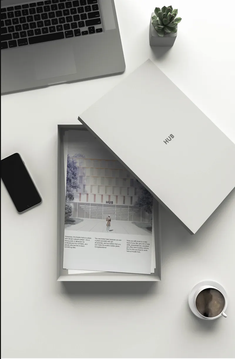 HUB welcome package: a branded box with an architectural brochure inside, photographed on a desk with a laptop, phone, coffee, and a succulent