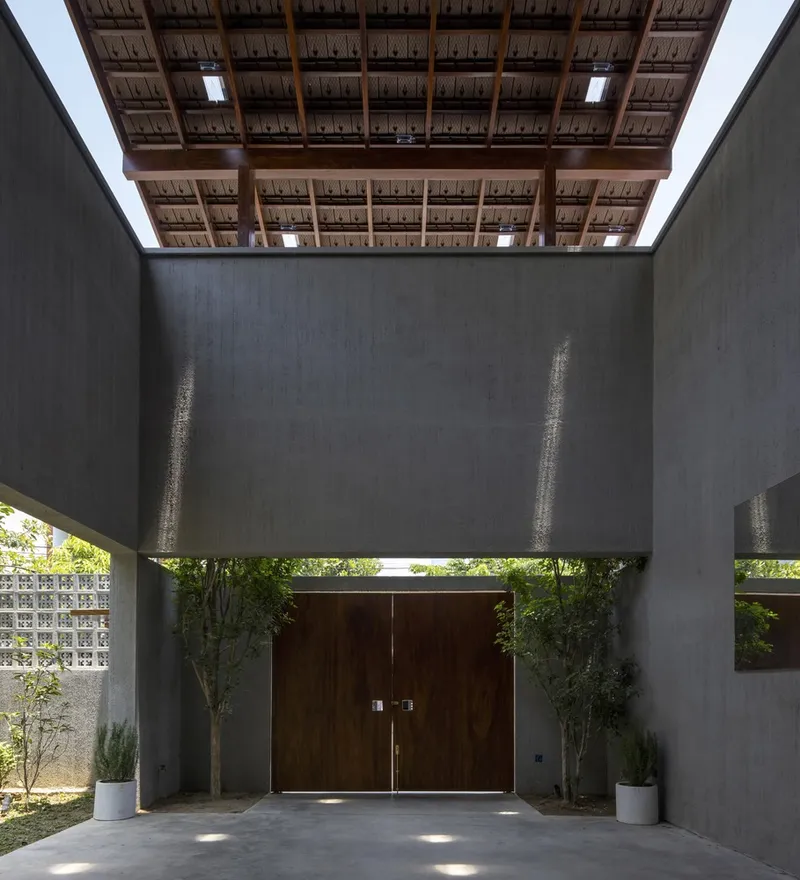 Covered entry with exposed timber and thatch ceiling above timber doors flanked by planters