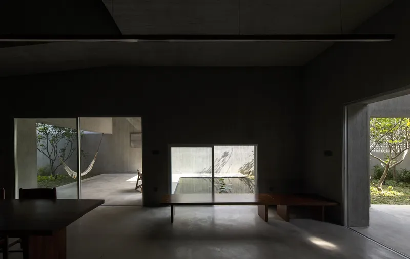 Living area with low timber furniture looking through glazed openings to multiple planted courtyards