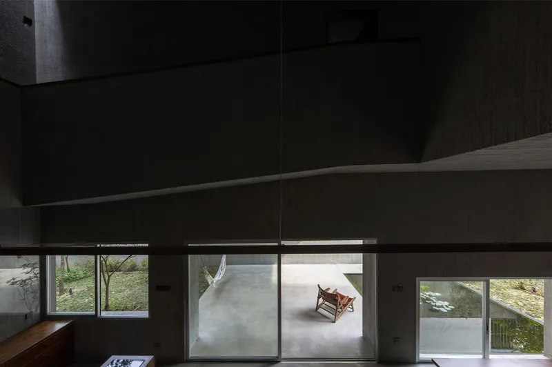 View through horizontal slot windows showing a rocking chair on a concrete terrace