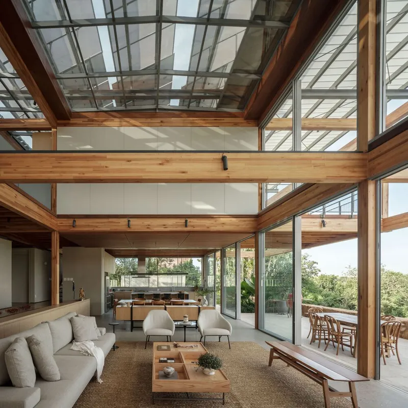 Double-height living room with exposed timber beams and glass skylight overlooking the landscape