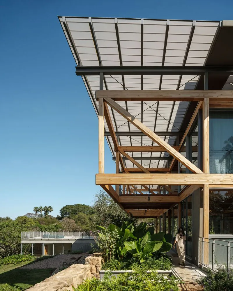 Detail of the cantilevered timber structure supporting translucent solar roof panels above a courtyard garden