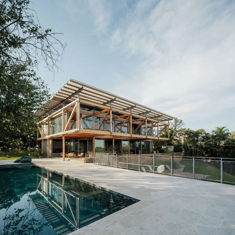 Rear terrace with reflecting pool and timber-framed residence under partly cloudy sky