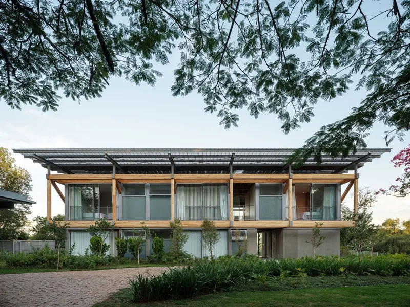 Front elevation showing timber frame supporting translucent roof above glazed upper level and stone-clad ground floor
