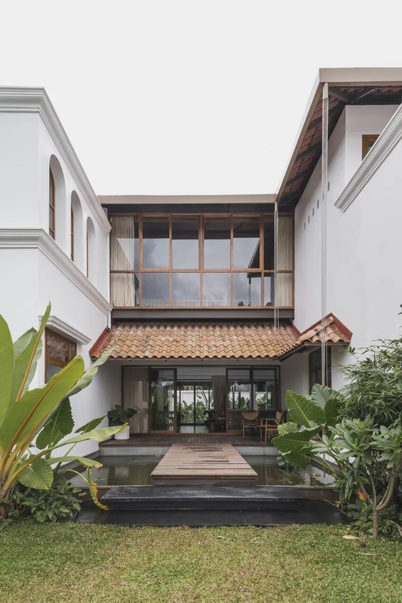 Courtyard elevation showing white stucco walls, timber bridge and clay tile roofs flanking a lawn