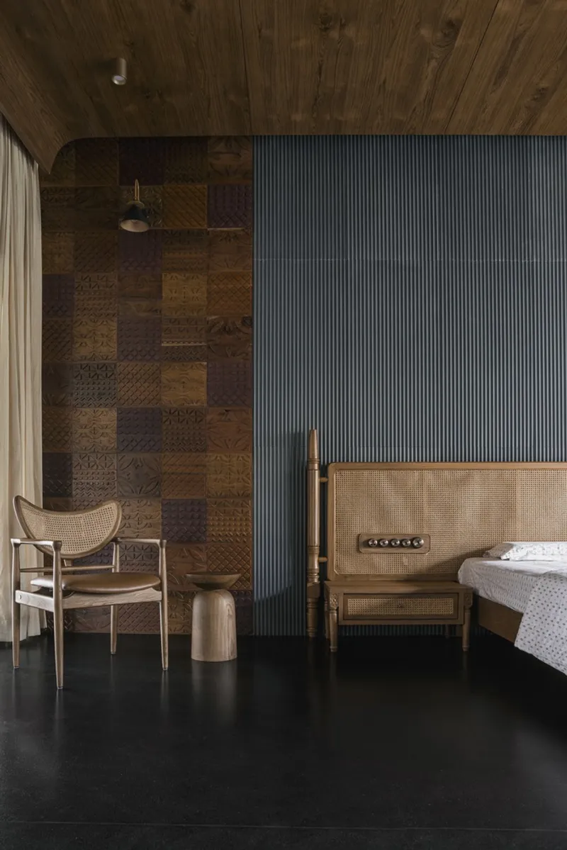 Bedroom interior with ribbed blue accent wall, patchwork timber wall and black stone flooring