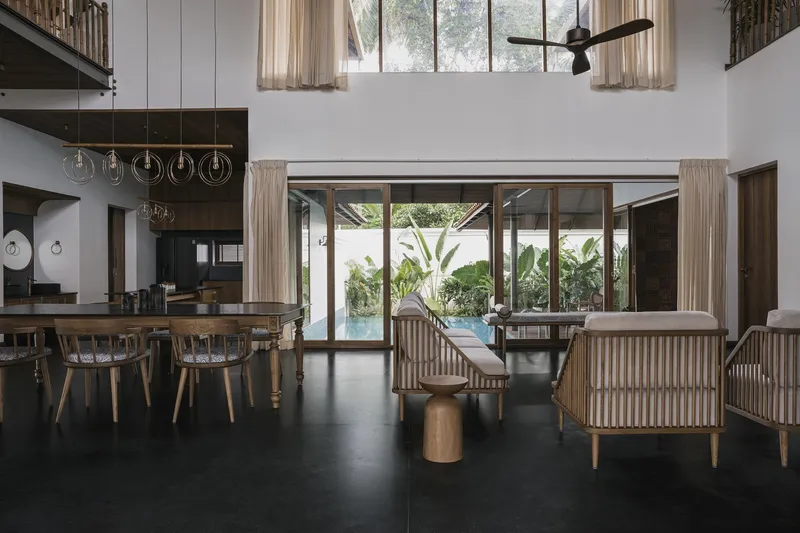 Open living area with dark concrete floor looking through glazed doors to pool and banana plants