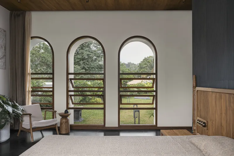 Three arched timber doors with horizontal rails opening to lawn and tree canopy beyond
