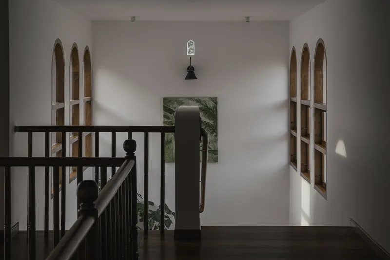 Upper landing with dark timber railing overlooking arched timber-framed windows in afternoon light