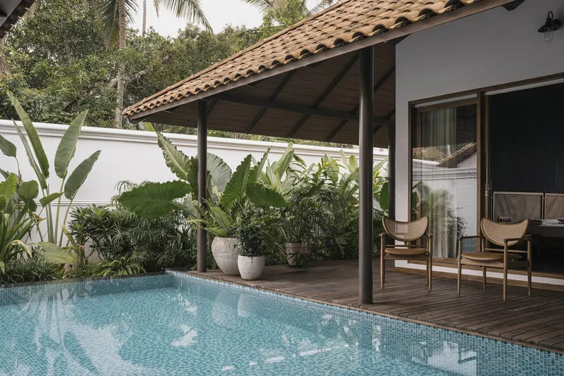 Covered terrace with timber deck and mosaic-tiled pool surrounded by banana plants and tropical greenery