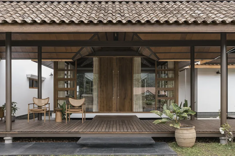 Sheltered timber deck terrace with steel columns, exposed trusses and clay tile roof under overcast skies