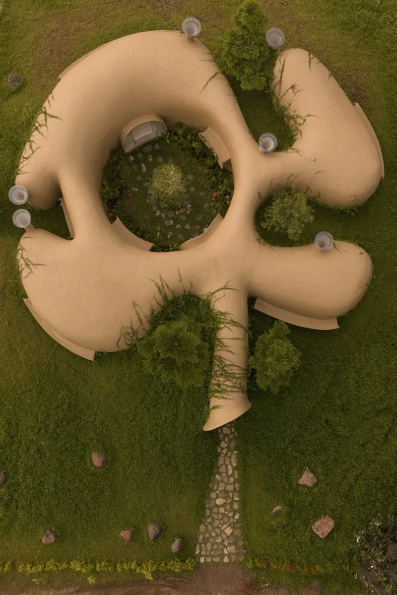 Aerial: the organic plan with lobed rooms radiating from a central courtyard, grass roof, stone path entry