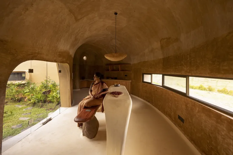 Kitchen: barrel-vaulted earth ceiling, built-in earthen counter and bench, strip windows to garden