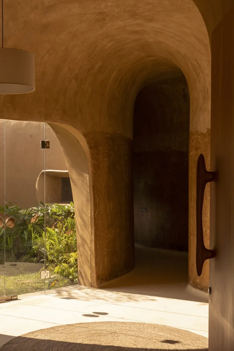 Doorway sequence: arched earth openings in perspective, garden light beyond, circular floor inlay, lime walls