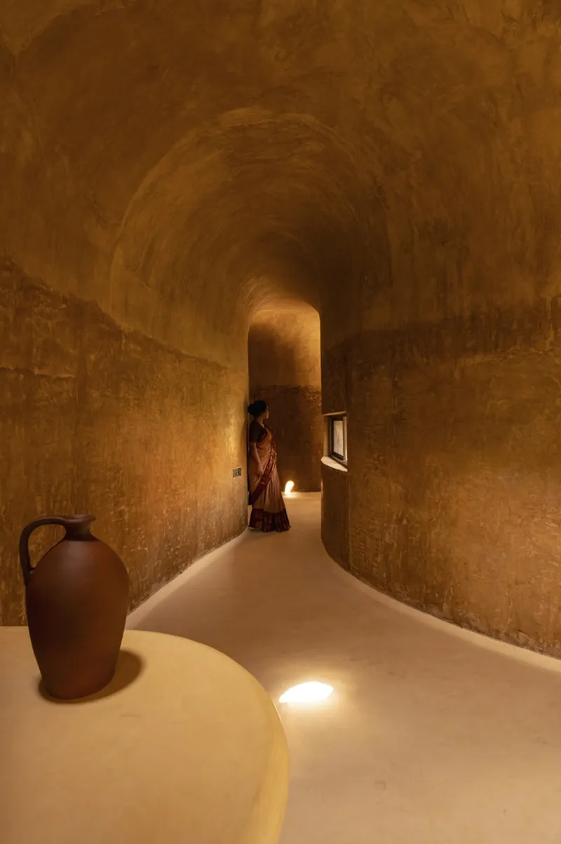 Curved corridor at night: earth walls, floor lights, narrowing passage, arched vault