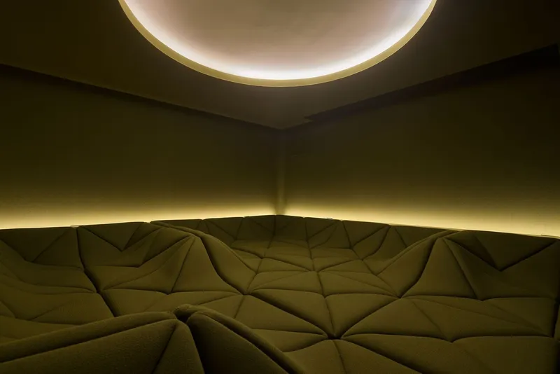 Detail of the geometric quilted seating surface beneath a circular illuminated ceiling recess