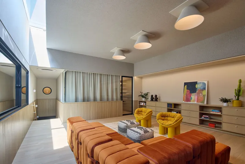 Living room interior with three domed pendant lights, fluted wood paneling, and full-height sheer curtain under skylight