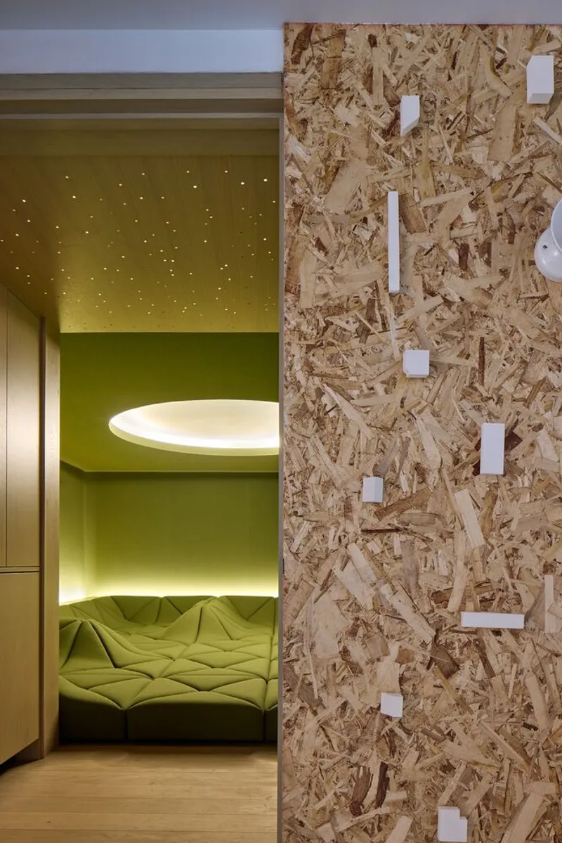 Oriented strand board wall with white blocks beside a yellow illuminated sleeping nook