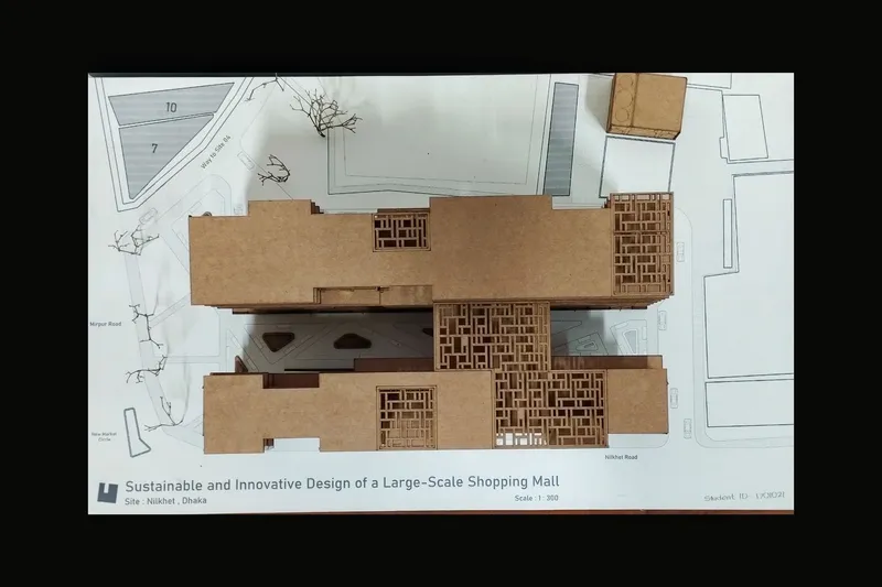 Physical cardboard study model of the project on its Nilkhet site plan: a rectangular massing with carved courtyards and open terraces that define the public routes through the block