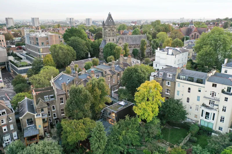 Aerial view shows the house nestled among Hampstead's residential gardens, with the church tower visible beyond.