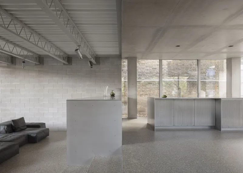 Ground floor with stainless steel island, dark leather sofa, and blockwork feature wall.