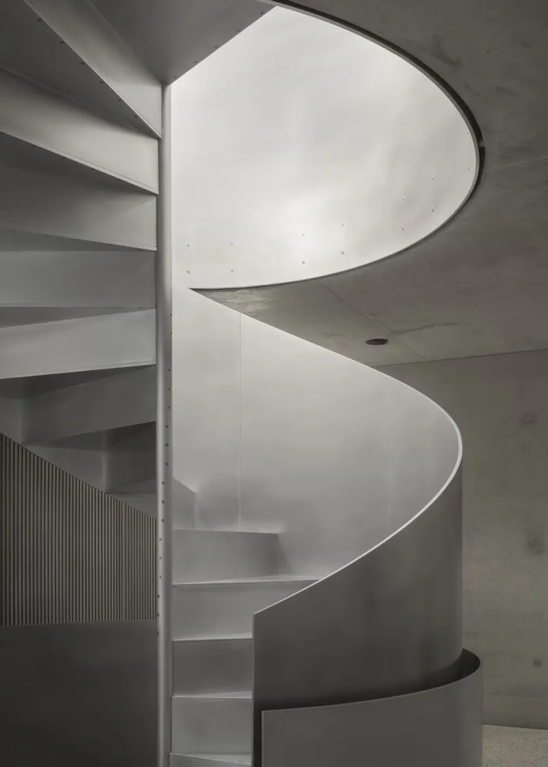Looking up the spiral stair from below, light floods through the oculus at the top.
