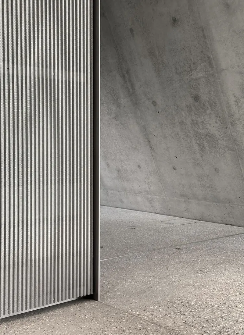 Material junction: corrugated metal meets concrete wall, revealing the assembly logic.