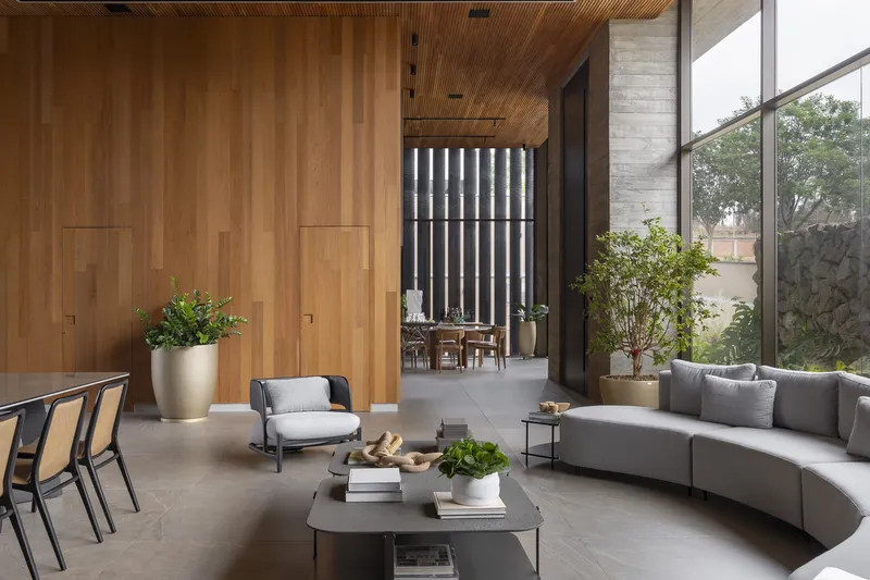 Double-height living room with timber-clad walls and ceiling overlooking interior courtyard through floor-to-ceiling glazing