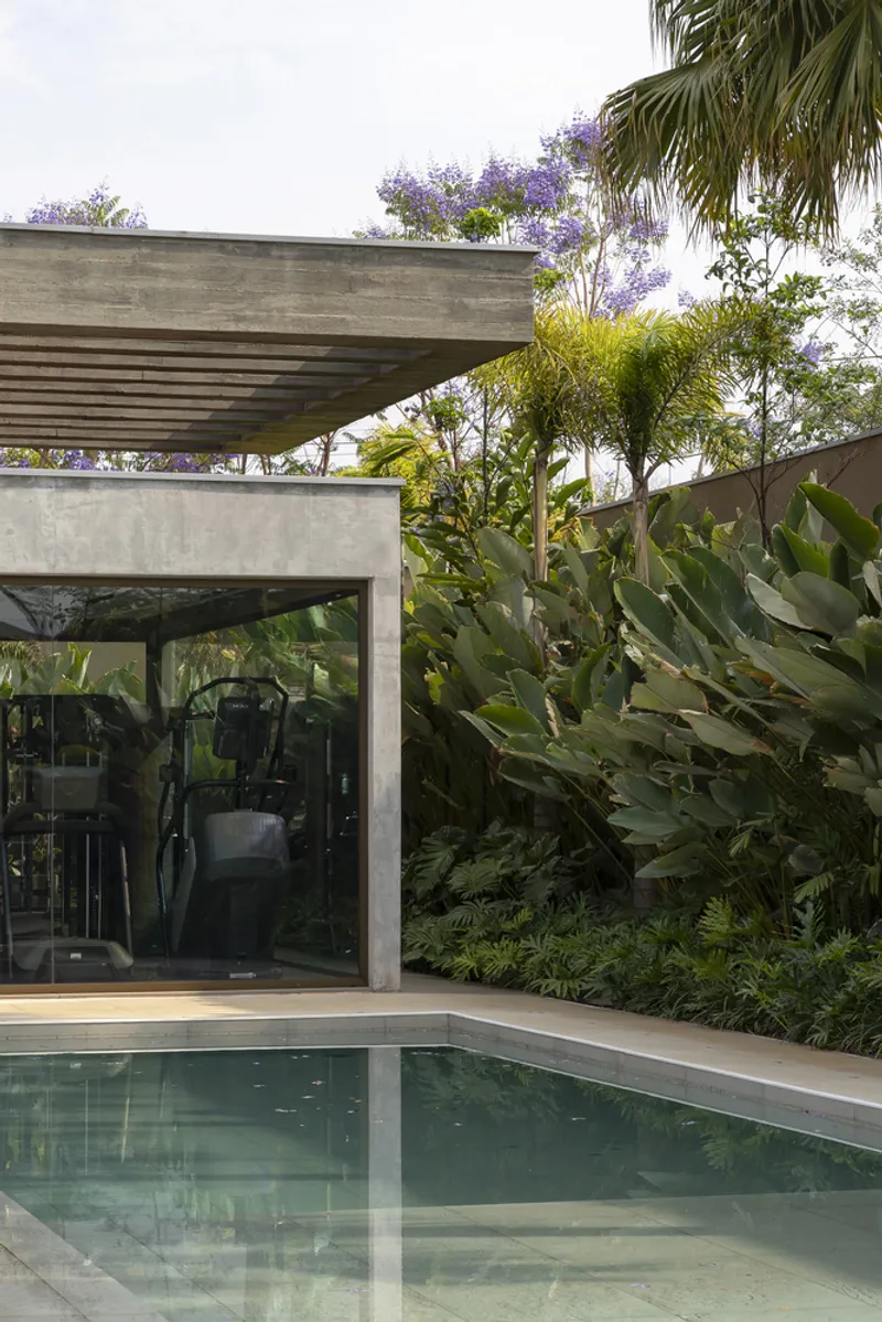 Glass pavilion beneath the cantilevered concrete roof with pool edge and tropical planting alongside