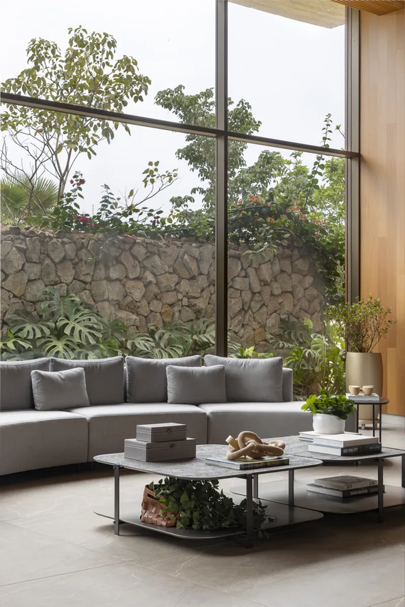 Living room with floor-to-ceiling glazing overlooking a stone retaining wall and planted garden