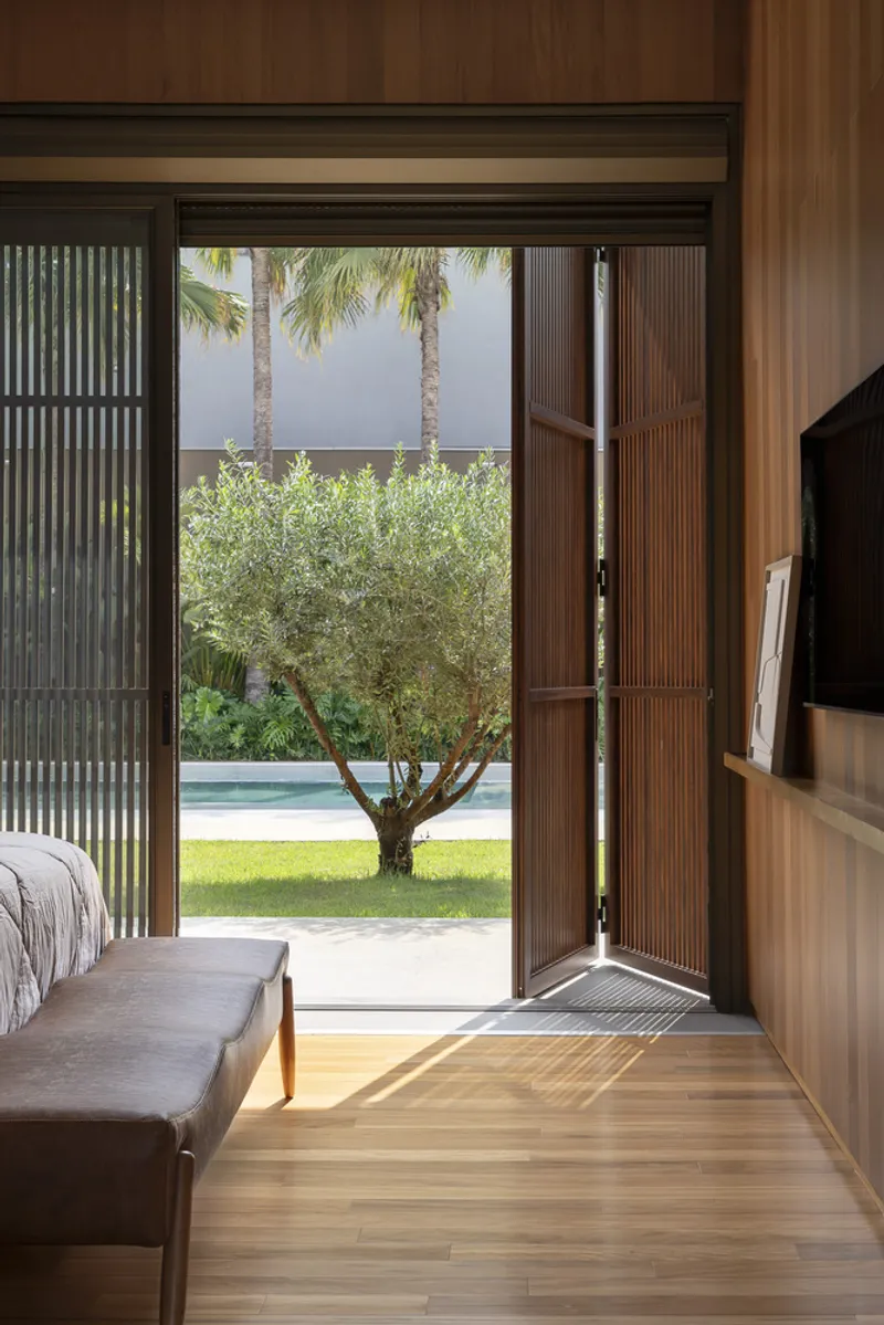 Bedroom with sliding glass doors opening to garden with palm trees and pool beyond
